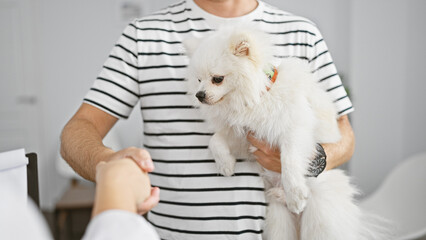 Handsome young caucasian man shaking hand with vet in a heartfelt greeting at the veterinary...