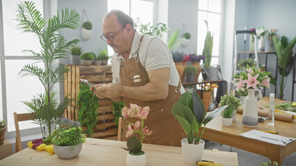 Mature man in apron using smartphone in flower shop with plants and arrangements in background.
