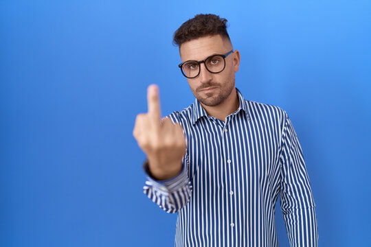 Hispanic man with beard wearing glasses showing middle finger, impolite and rude fuck off expression