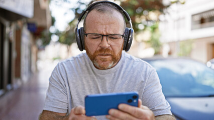 Caucasian man using smartphone wearing headphones at street