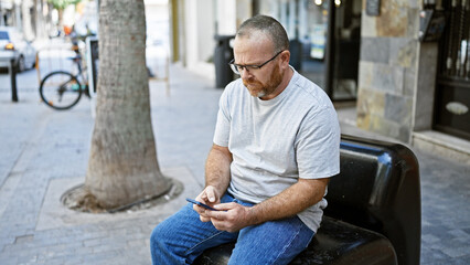 Attractive middle-aged caucasian man, with a serious expression, avidly typing a message on his...