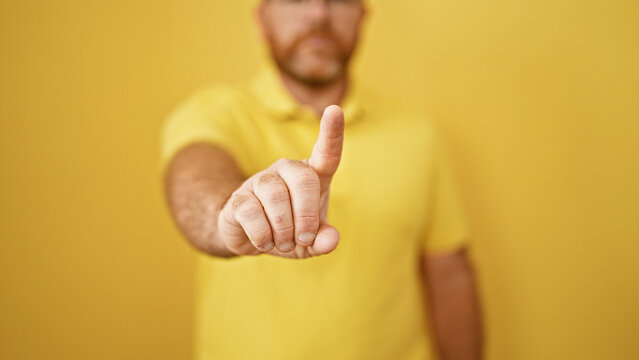 Caucasian man saying no with finger over isolated yellow background