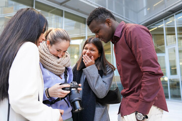 Multi-ethnic friends checking the pictures on a digital camera screen