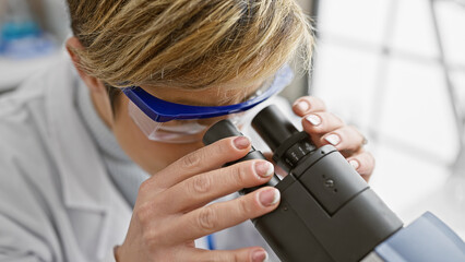 A young woman using a microscope in a laboratory setting, signifying research and scientific...