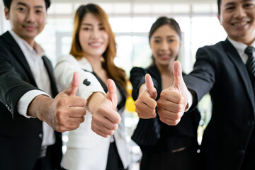Close up of a group of diverse businesspeople showing raised thumbs at the camera. Recommendation of good choice. The diversity of African and Caucasian businesspeople gives a positive response. - 785327487