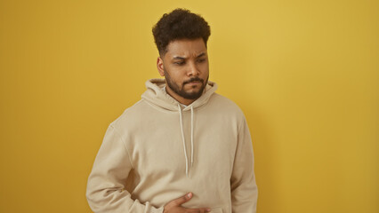 Obraz premium Portrait of a pained african american man with a stomachache isolated against a yellow background
