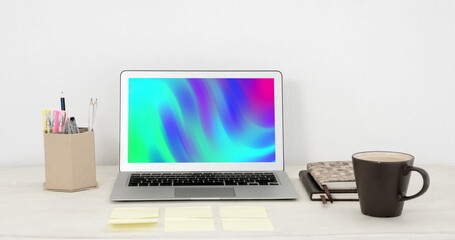 Image of laptop with colorful moving shapes on screen on desk