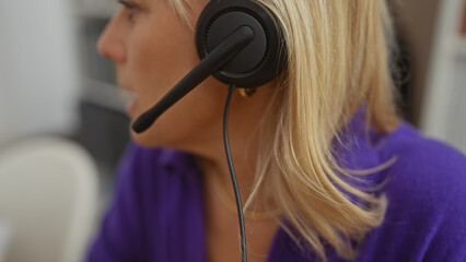 A side-view portrait of a focused blonde woman wearing a headset, symbolizing remote work from a...