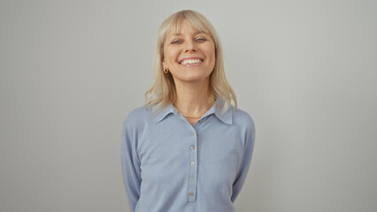 A smiling caucasian woman with blonde hair in a blue shirt against a white background portrays...