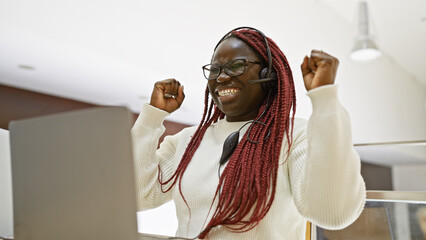 African american woman with braids celebrates success in an office setting, exemplifying workplace...