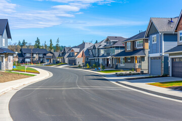 A street view of a new construction neighborhood with larger landscaped homes and houses with yards.