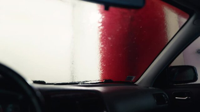Inner Glow: Witness the magic of an automatic car wash as your vehicle is bathed in a shimmering cascade of foam, filmed from inside to highlight the cleansing process in action.
