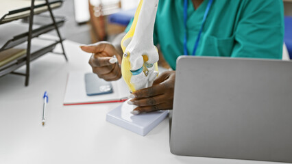 African american woman physiotherapist explaining a knee model in a rehab clinic
