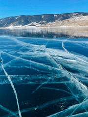Texture of beautiful blue ice with cracks and air bubbles in the frozen lake.