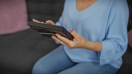 Senior woman in blue holding a photo frame at home, showing a memory or storytelling.