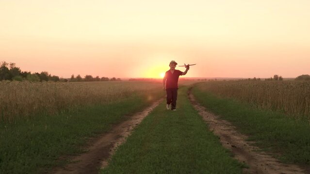 child kid baby boy runs across field with rainbow kite hands sunset, children's dream flying, airplane pilot, happy boy playing with flying kite park sunset, feeling freedom vacation, flying kite