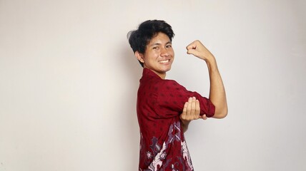 Handsome Asian young man dressed in batik posing showing strong arms