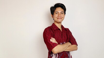 Handsome young Asian man dressed in batik posing crossed arms