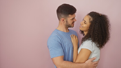 A loving couple embracing each other against a pink background, sharing a moment of affection and togetherness.