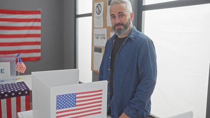 Bearded man in denim voting at an american electoral center with flag