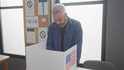 Bearded man in denim voting at an american electoral center with us flag.