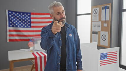 Blond bearded man pointing in american voting center with flag