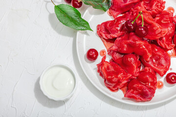 Dumplings, filled fresh cherries. Ripe fruits, sweet sauce, sour cream. Traditional Ukrainian dish