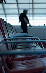 A passenger walks through an airport terminal and past blurry rows of empty chairs on his way to the boarding gate for his flight in Paris