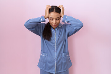 Young arab woman wearing blue pajama suffering from headache desperate and stressed because pain...