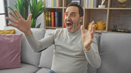 Enthusiastic middle-aged man with beard celebrating in a cozy living room interior