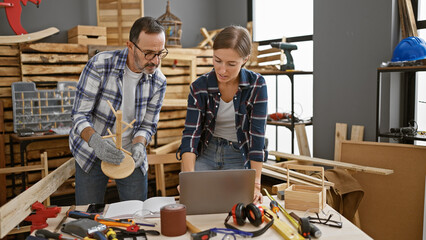 Two professional carpenters, partners in timber furniture business, engrossed in serious...