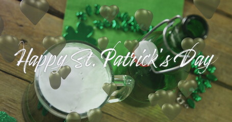 Image of st patrick's day text and green hearts and glass of beer on wooden background