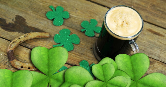 Naklejki Image of st patrick's day shamrock and glass of beer on wooden background