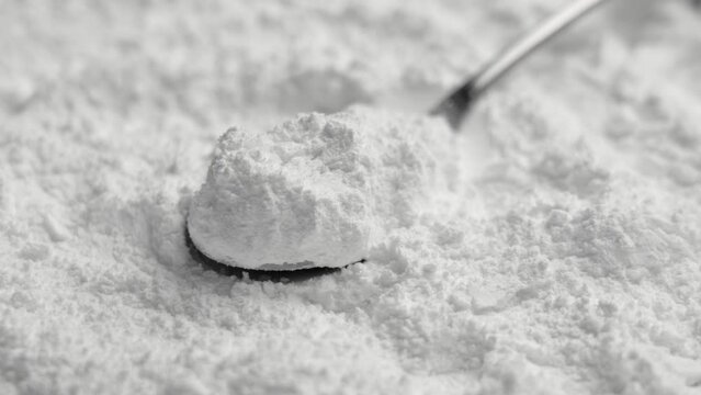 Nutrient dietary potassium chloride powder in a metal measuring spoon close up. Medical electrolyte mineral supplement. Rotation