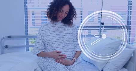 Fast moving clock over happy pregnant biracial woman rubbing belly in hospital room