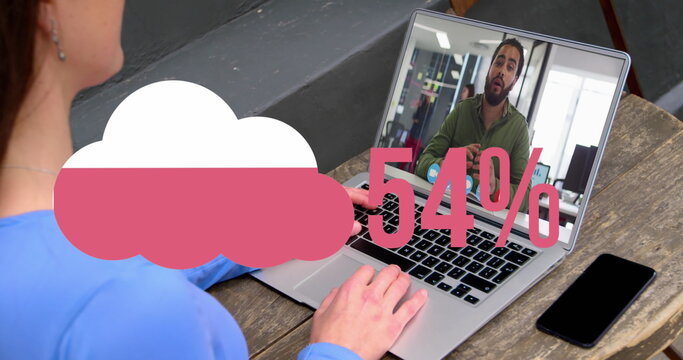 Image of cloud upload icon against rear view of woman having a image call on laptop at a cafe