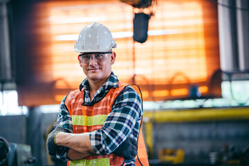 Portrait of male foreman factory wearing hardhat in arms crossed looking at camera standing at the industry factory. Construction worker or builder career in positive attitude. copy space