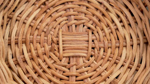 Textured pattern of empty handcraft rattan wicker bowl close up. Top view. Rotation