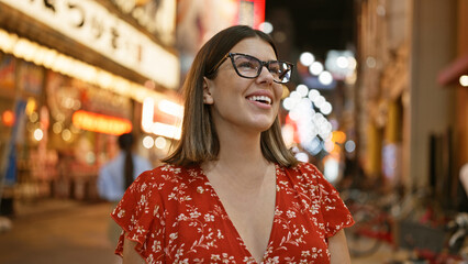 Capturing the joyful night, beautiful hispanic woman in glasses enjoying shinsekai street, laughter...