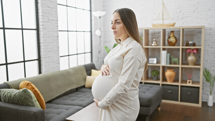Pregnant hispanic woman standing in a cozy living room, embodying expectancy and motherhood