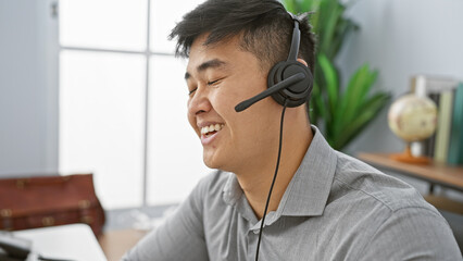 Smiling asian man with headset working in a modern office expressing approachability and professionalism.