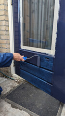 painting a door with blue paint with a roller - 785347433