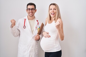 Young woman expecting a baby with doctor screaming proud, celebrating victory and success very excited with raised arm
