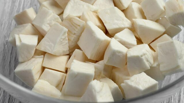 Raw chopped cassava root in kitchen glass bowl. Fresh Yucca tuber slices. Organic healthy ingredients. Rotation