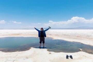Happy woman with raised arms standing in the water of Lake Uyuni, Bolivia.