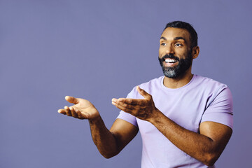 young black man with beard and mustache smiling and looking away at copy space hand signal isolated blue background