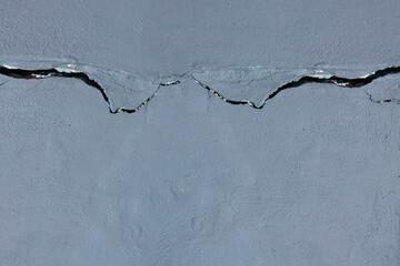 Horizontal cracked concrete wall or floor covered with gray cement mortar