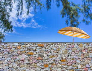 Parasol de plage derrière mur de pierres 