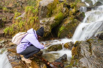Woman hiker contemplating a waterfall on a sunny day
