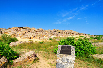 Summer landscape - view of the mound of sandstone boulders with a sign Archaeological site, ancient place of worship, archeological preserve Kamyana Mohyla, Ukraine